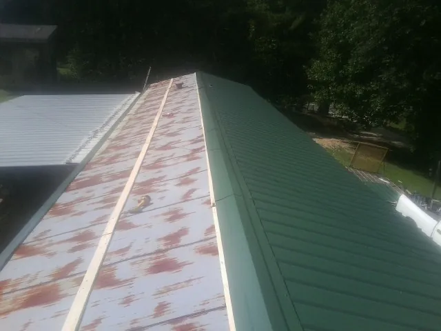 Old rusted panels beside newly installed green metal roofing — Wind Damage Roof Repair by Roofing Brothers in Pico Rivera