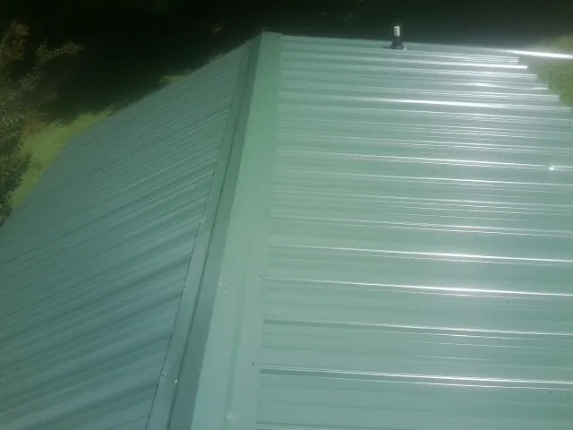 New green metal panels meeting at the ridge of a roof — Flat Roof Repair work by our crew in Pico Rivera