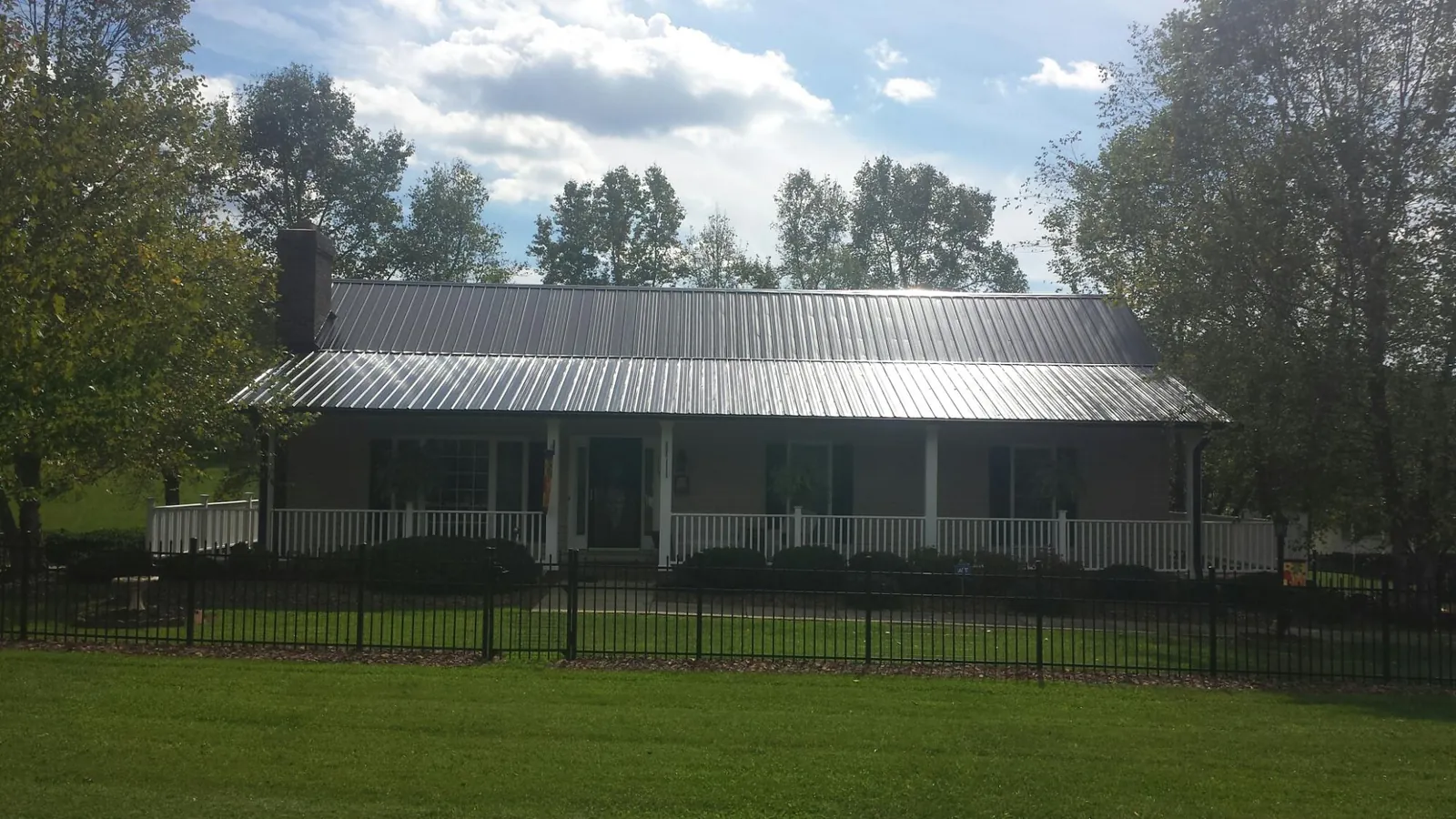 Gray metal roof on a brick ranch with a full width front porch — Gutter Guard Installation work by our crew in Pico Rivera