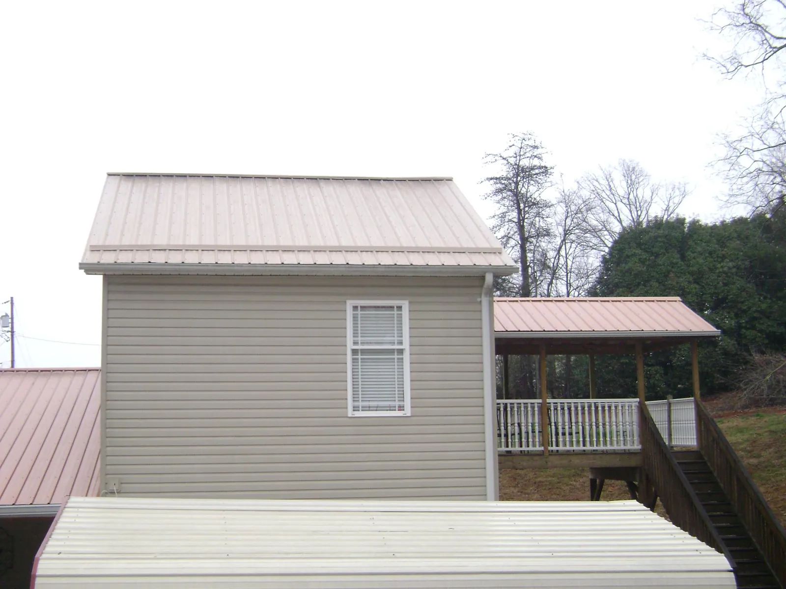 Tan metal roofs on a two story addition and attached porch, from a Roof Replacement job in Pico Rivera